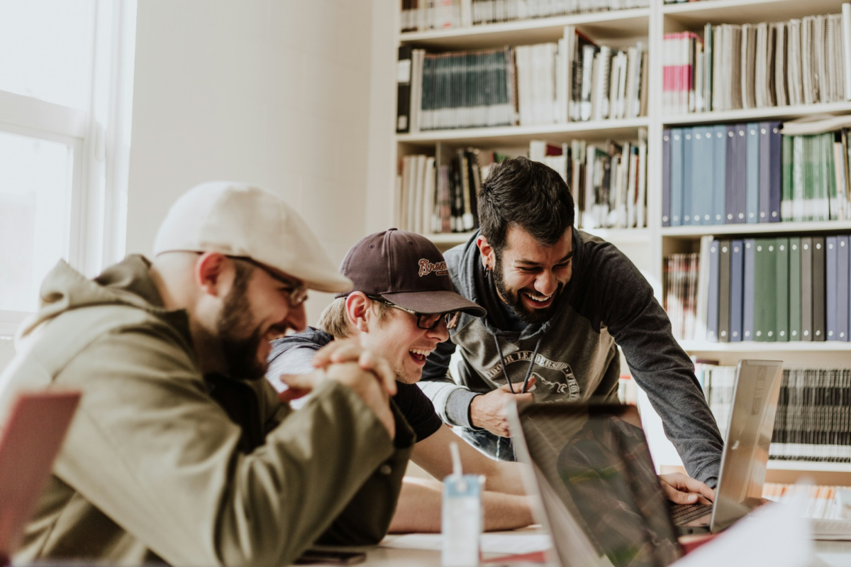 three men smiling looking at a computer screen